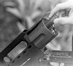 A 12-ga cartridge being loaded into the cylinder, above which is the part that locked into the rear latch to keep the gun firmly closed. 