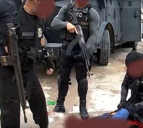 As their colleague handcuffs a suspect on the ground, other civil police officers watch, holding (L-to-R) another HK with the stock fully retracted and a 7.62x39mm AK-type rifle with a 40-round waffle magazine and side-folder stock (a polymer-construction Tapco variant?), plus a VFG assembly. The guy opening the armored car's door in the distant background has an M16A2 Commando hanging from his neck. That's a gun mix, huh?