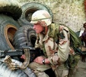 A Somali man sits back and smokes Aug. 31, 1993, as a U.S. soldier guards the front gate of a garage that was being searched for arms. (Alexander Joe/AFP via Getty Images)