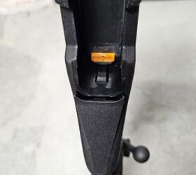 The pistol grip storage compartment opens by pressing the black tab just below the orange piece