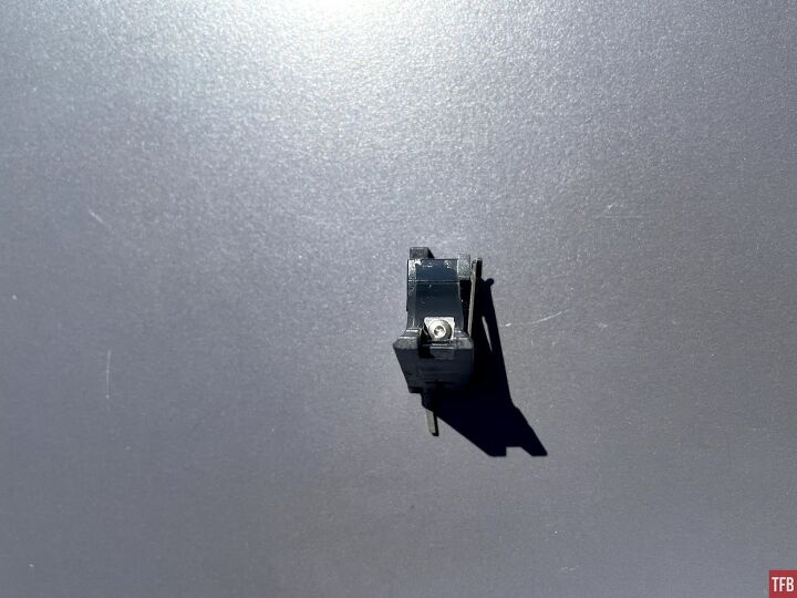 The screw and c-clip washer which holds the sear assembly in the factory trigger housing.